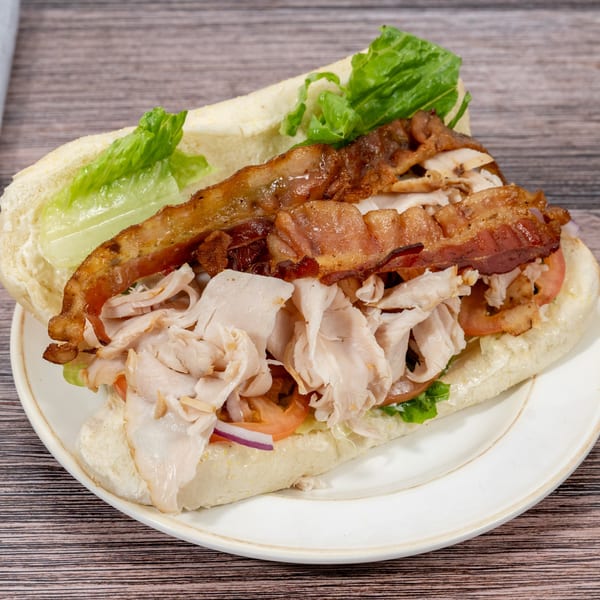 A Huntington Deli & Market turkey and bacon sub sandwich with lettuce, tomato, and onion.