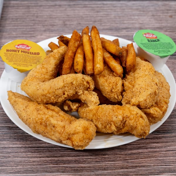 A plate of Huntington Deli & Market's crispy chicken tenders and golden french fries with dipping sauces.